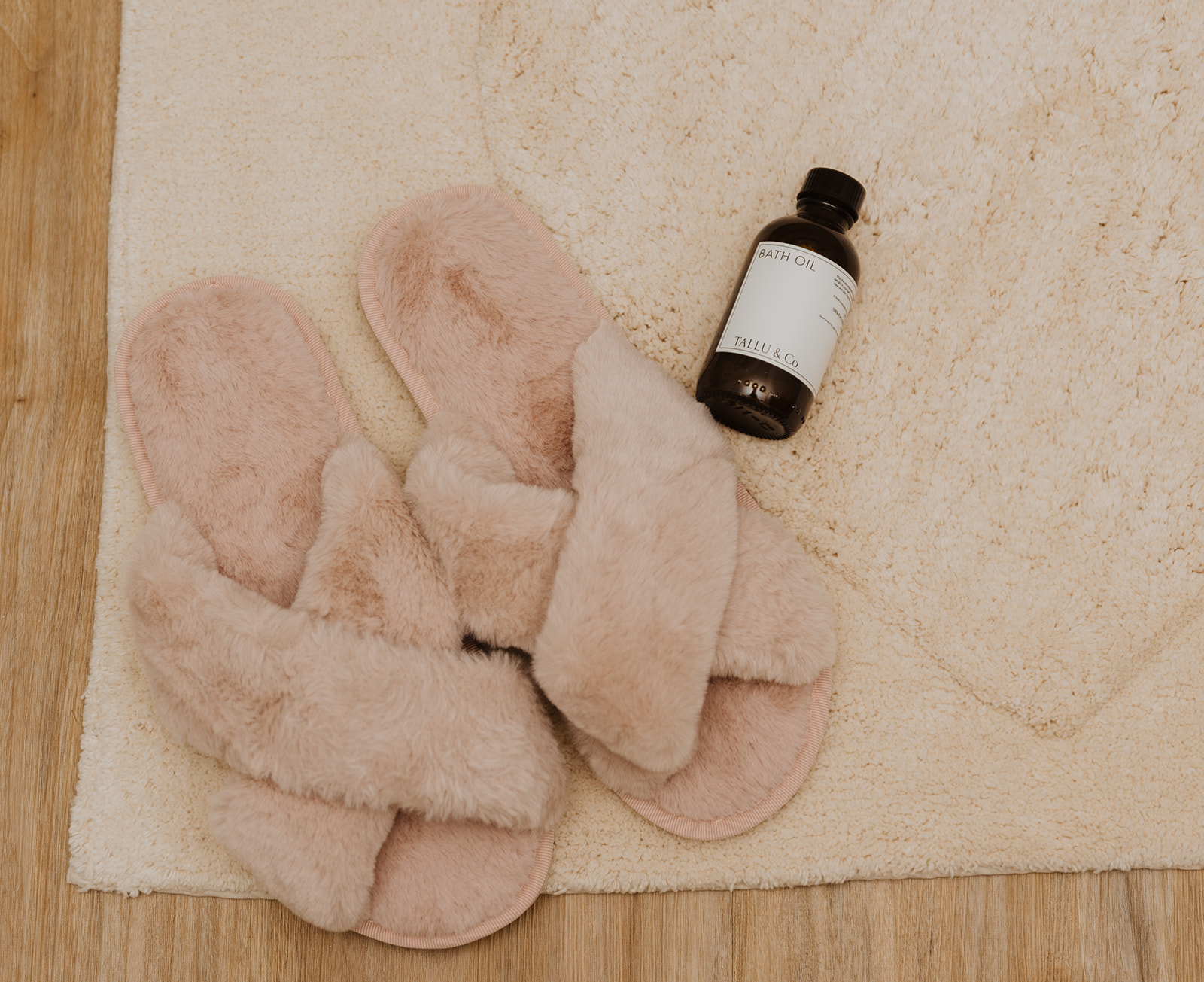 slippers and bath oil on cream bath mat