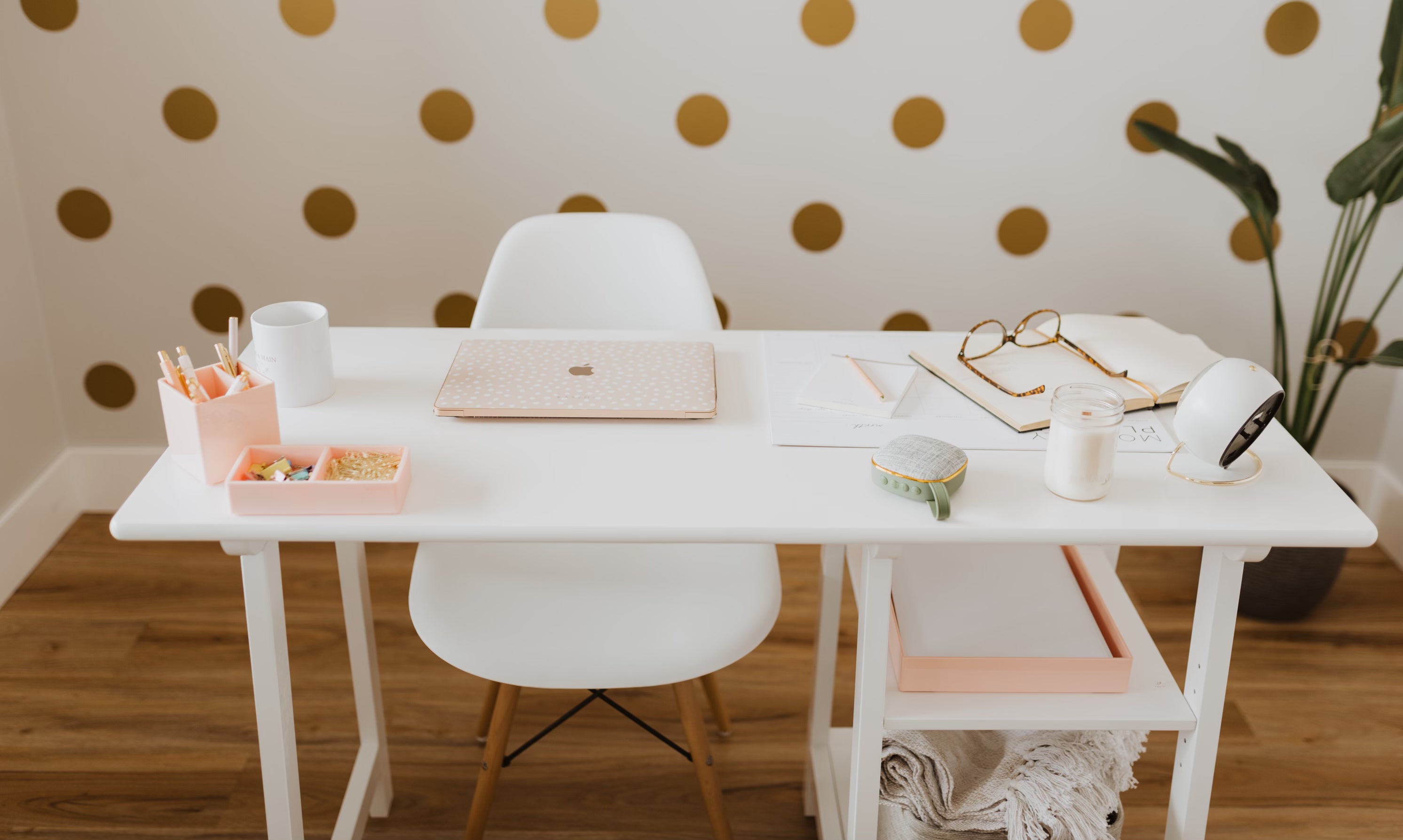 White desk and chair in office with gold polka dot wallpaper